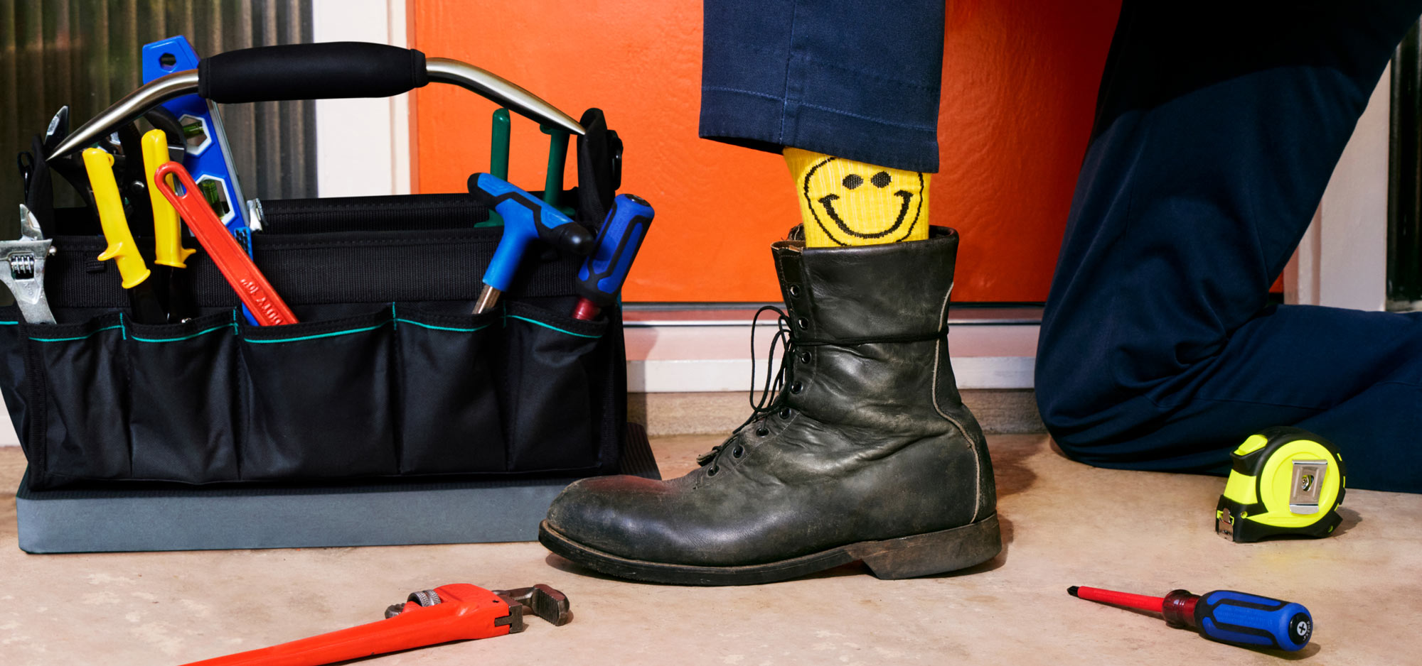 Contractor with tool bag wearing smiley face socks.