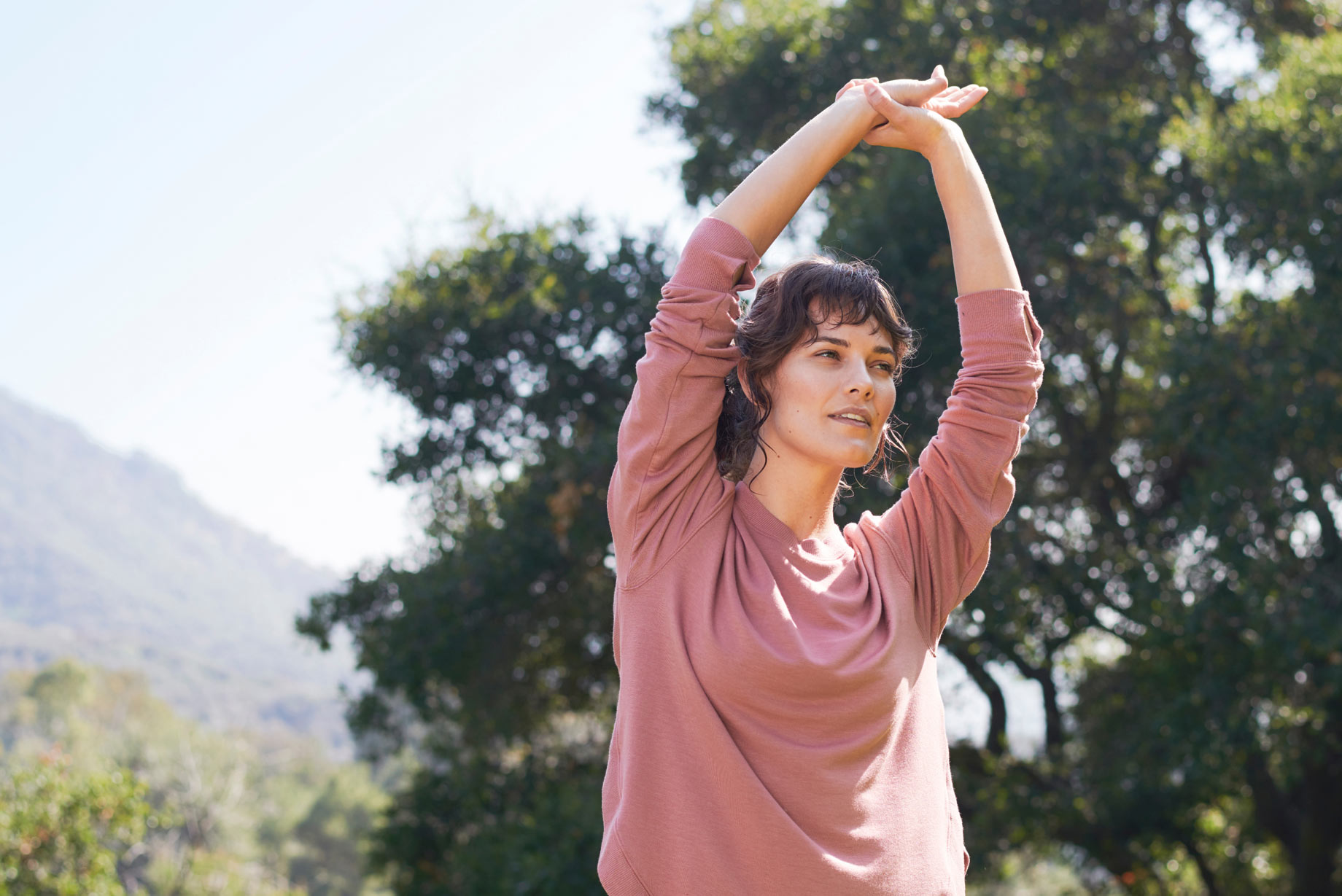 Woman stretching with arms above head.